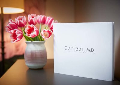 A vase of pink/white tulips in Capizzi MD's entryway next to introduction book.