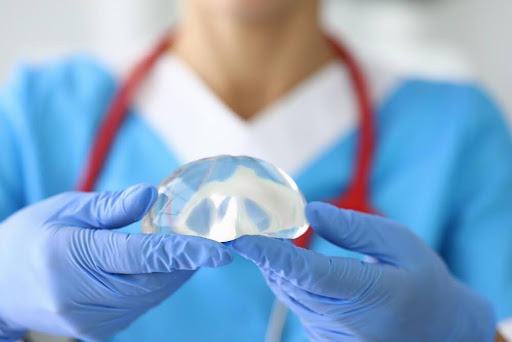 A doctor holding a breast implant explaining the differences in gummy bear implants vs silicone.